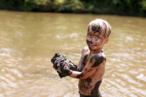 A muddy boy at a lake