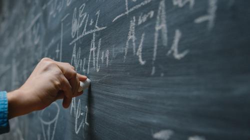A hand writing something on the blackboard